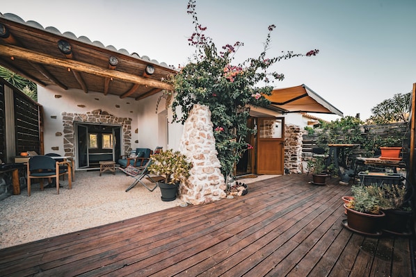 A patio with wooden flooring, stone walls, and potted plants.