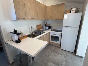 A compact kitchen with a sink, microwave, stove, and refrigerator.