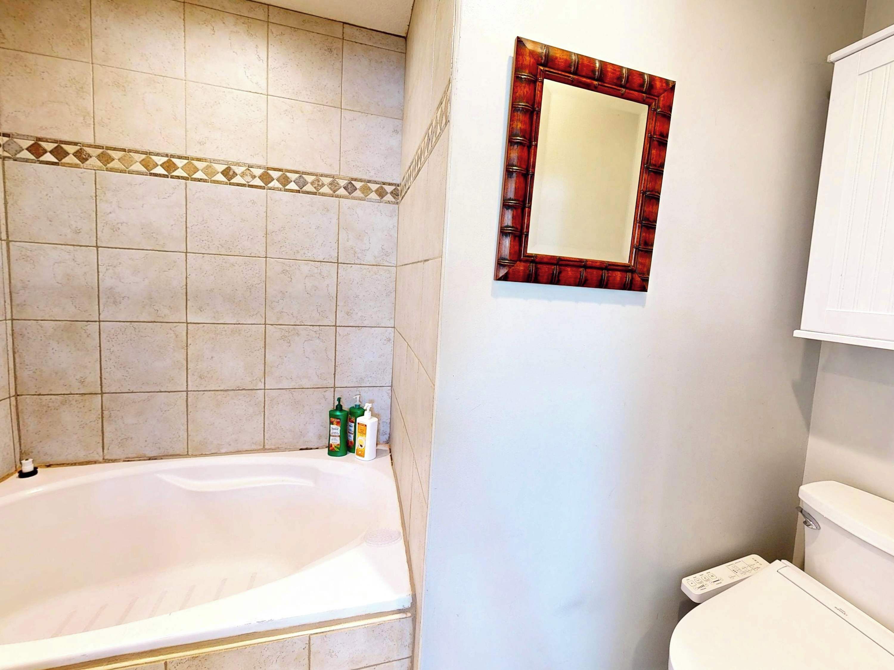 Un baño con bañera, inodoro y espejo.