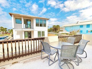 Ein modernes, zweistöckiges Gebäude mit Balkon, Außenbereich und einem Pool im Hintergrund.