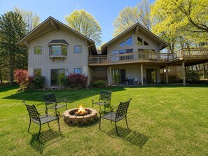 Een huis met twee verdiepingen, een terras en een vuurkorf in de voortuin.