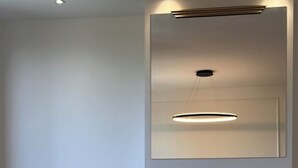 Moderni huone, jossa on puinen pöytä, tummanruskea tuoli ja seinälle asennettu valaisin.
