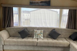 A beige sofa with a patterned cushion, a floral pillow, and two dark pillows.