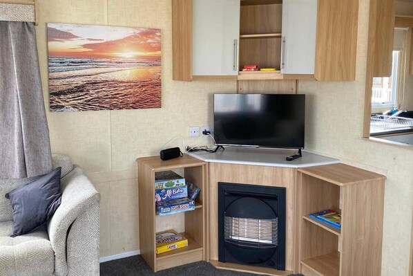A compact room with a TV, a bookshelf, a small heater, and a couch.