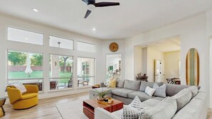 A spacious living room with a large gray sofa, a yellow armchair, and a wooden coffee table. - Modern Home Near Lake LBJ With Enclosed Yard, Patio, Grill & Central AC (Horseshoe Bay)