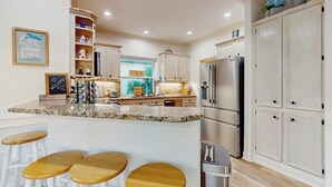 A kitchen with a granite countertop, stainless steel appliances, and wooden stools. - Modern Home Near Lake LBJ With Enclosed Yard, Patio, Grill & Central AC (Horseshoe Bay)