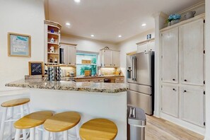Eine Küche mit Granit Arbeitsplatte, Edelstahlgeräten und Holzbarhocker.