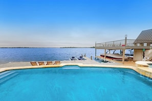 A pool with lounge chairs, a covered deck, and a view of the water. - Luxe Lakefront Retreat With Private Pool, Spa, Lakeside Terrace, Gourmet Kitchen (Horseshoe Bay)