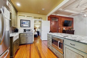 Una cocina con armarios de madera, refrigerador, microondas, horno y televisor montado en la pared.