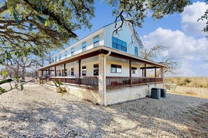 A modern two-story building with a covered porch, stone foundation, and large windows. - Peaceful Home With Fire Pit, Gazebo, Patio, & Amazing Deck Views - Dog-friendly (Fredericksburg)