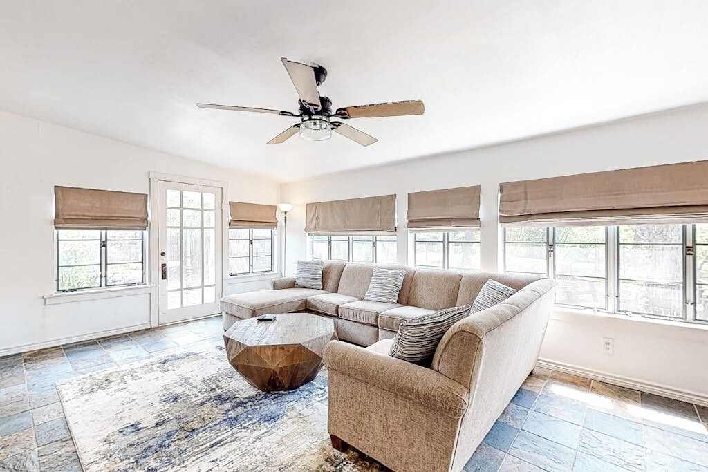 A spacious living room with a sectional sofa, a coffee table, and a ceiling fan.