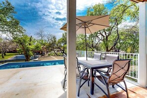 A covered patio with a pool, outdoor furniture, and a view of trees and a pool. - Waterfront Home With Game Room, Decks, Pool, Smart Tvs, Kayaks, & Gas Grill (Kingsland)