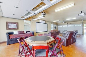 A conference room with a round table, chairs, a projector, and a screen. - Waterfront Home With Game Room, Decks, Pool, Smart Tvs, Kayaks, & Gas Grill (Kingsland)