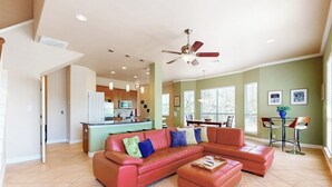 A spacious living room with a sectional sofa, a ceiling fan, and a kitchen in the background. - Waterfront Home With Game Room, Decks, Pool, Smart Tvs, Kayaks, & Gas Grill (Kingsland)