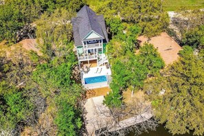 A two-story house with a swimming pool, surrounded by dense trees and a rocky landscape. - Waterfront Home With Game Room, Decks, Pool, Smart Tvs, Kayaks, & Gas Grill (Kingsland)