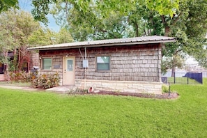 A small wooden house with a shingled roof, a front door, and a small porch. - Classic Lakefront Cottage With Private Dock, Lovely Lake View, Backyard & Wifi (Kingsland)