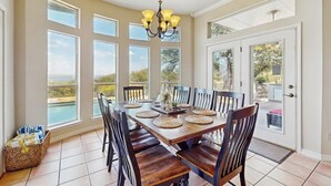 A dining area with a large table, chairs, and a chandelier. - Sacred Vista Opulent Hill Country Gem Amazing Patio & Great View (Horseshoe Bay)