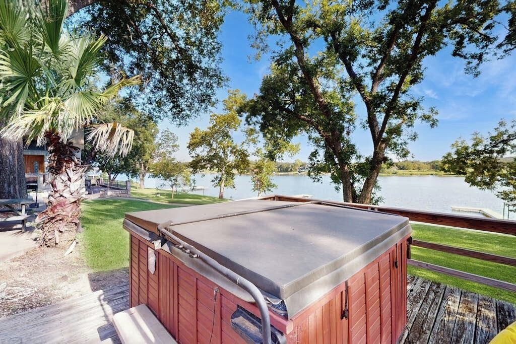 A hot tub on a wooden deck with a lake view.