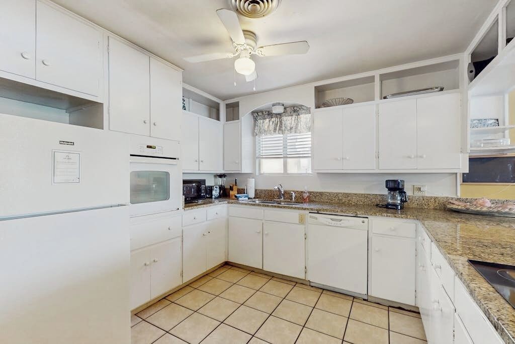 A kitchen with white cabinets, a microwave, a coffee maker, and a ceiling fan.