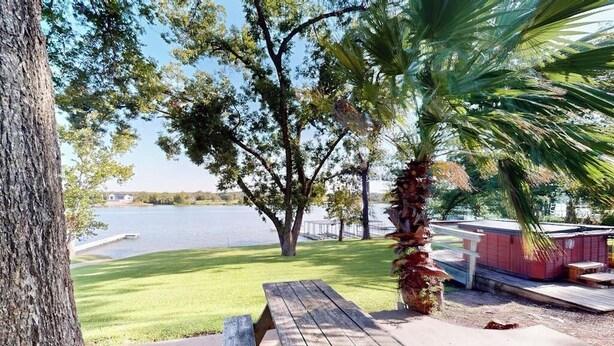 Ein Holztisch, eine Palme und Blick auf einen See.