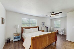A bedroom with a wooden bed, two bedside tables with lamps, a ceiling fan, and two windows with blinds. - Idyllic Home With Firepit, Gazebo, Patio, & Amazing Deck Views - Dog-friendly (Fredericksburg)