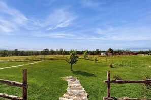 A rural landscape with a stone pathway leading through a green field, wooden fence posts, and distant farm buildings. - Idyllic Home With Firepit, Gazebo, Patio, & Amazing Deck Views - Dog-friendly (Fredericksburg)