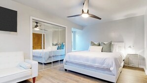 A modern bedroom with a large bed, a white sofa, a ceiling fan, and a wardrobe with a mirror. - Dog-friendly Waterfront Retreat With a Washer/dryer, Furnished Patio, & AC (Horseshoe Bay)