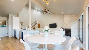 A modern kitchen with white cabinets, a dining area with a round table and white chairs, a staircase, and a fireplace. - Dog-friendly Waterfront Retreat With a Washer/dryer, Furnished Patio, & AC (Horseshoe Bay)