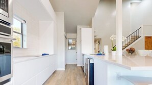 A modern kitchen with white cabinetry, a wooden floor, and a view into the living area. - Dog-friendly Waterfront Retreat With a Washer/dryer, Furnished Patio, & AC (Horseshoe Bay)