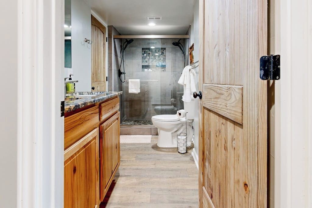 Ein schmales Badezimmer mit Dusche, Toilette und Holzausstattung.