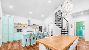 A modern kitchen with white cabinets, a wooden dining table, and a spiral staircase. - Lakefront Dog-friendly Home With Kayaks, Sup's, Huge Screened Porch (Burnet)