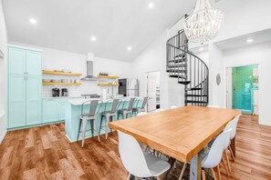 A modern kitchen with white cabinets, a wooden dining table, and a spiral staircase. - Lakefront Dog-friendly Home With Kayaks, Sup's, Huge Screened Porch (Burnet)