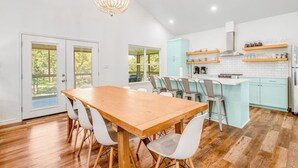 A modern kitchen with a wooden dining table, white chairs, and a light blue island. - Lakefront Dog-friendly Home With Kayaks, Sup's, Huge Screened Porch (Burnet)