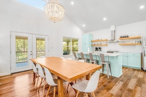 A modern kitchen with a wooden dining table, white chairs, and a light blue island. - Lakefront Dog-friendly Home With Kayaks, Sup's, Huge Screened Porch (Burnet)