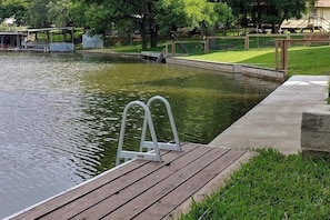 A wooden dock extending into a calm body of water, surrounded by grassy areas and trees. - Lakefront Dog-friendly Home With Kayaks, Sup's, Huge Screened Porch (Burnet)