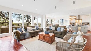 A spacious living area with a sofa set, a coffee table, and wicker chairs. - Natural Cliffside Oasis With Impressive Views, Gas Fireplace and Dock (Spicewood)
