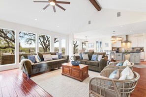 A spacious living area with a sofa set, a coffee table, and wicker chairs. - Natural Cliffside Oasis With Impressive Views, Gas Fireplace and Dock (Spicewood)
