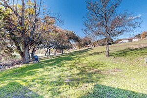 Un área de parque con césped, árboles y una parrilla.