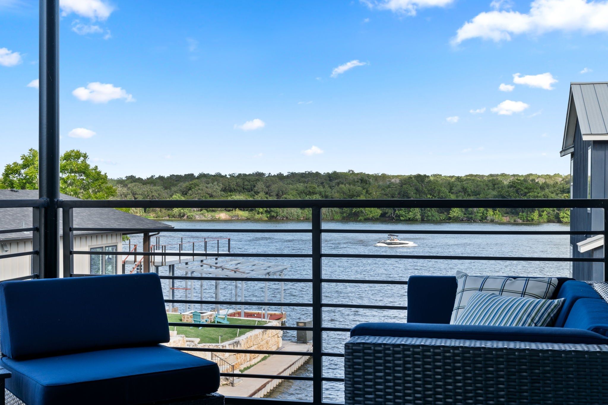 Un balcone con vista su una distesa d'acqua, un molo e una zona boschiva.