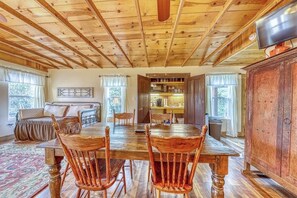 A dining area with a wooden table and chairs, a sofa, and a cabinet. - Adorable Studio Cabin With Covered Porch, Near Main Street, 2 Dogs OK (Fredericksburg)