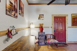 Ein Zimmer mit einem Holztisch, einem Stuhl, einer roter Tür und Wandbildern.