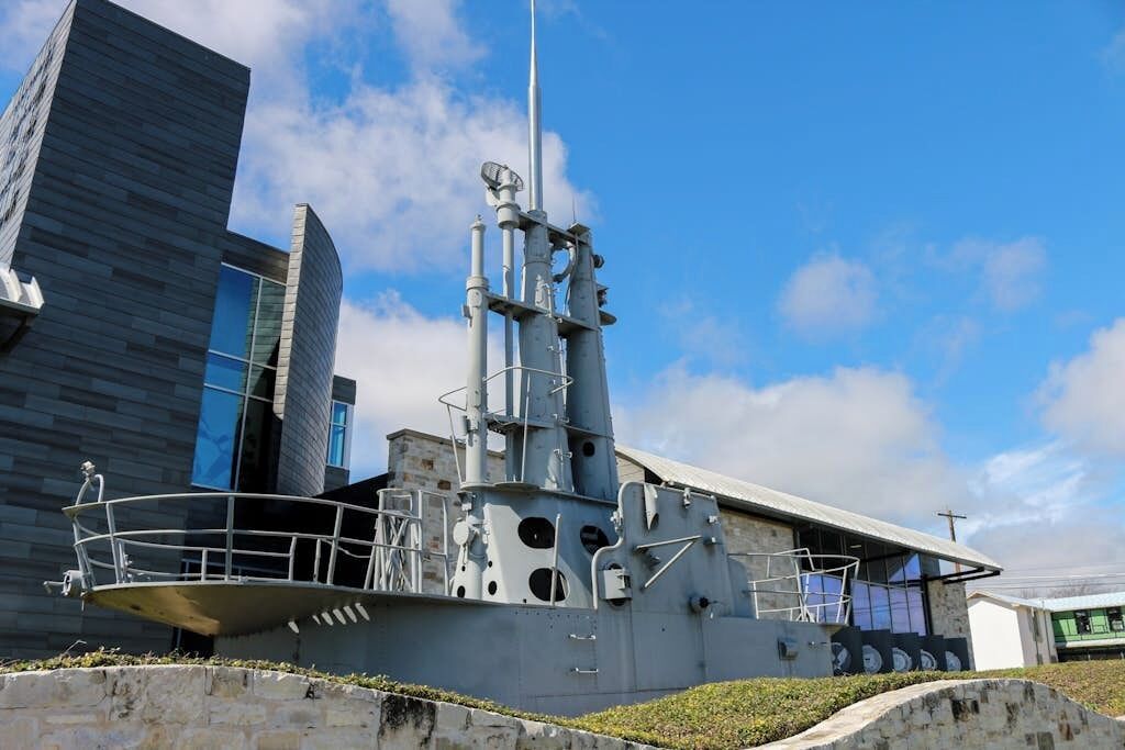 Ein großes, modernes Schiff liegt in einem Hafen, der von einem wolkenlosen Himmel überdacht wird.