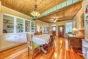 A spacious kitchen with wooden floors, a dining table, and cabinets. - Historic Fredericksburg Farmhouse - Hill Country Views - Wine Trail - Snowbird (Fredericksburg)