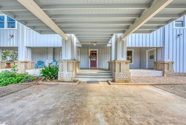 A covered entryway with a red door, concrete pillars, and steps leading to a porch area. - Historic Fredericksburg Farmhouse - Hill Country Views - Wine Trail - Snowbird (Fredericksburg)
