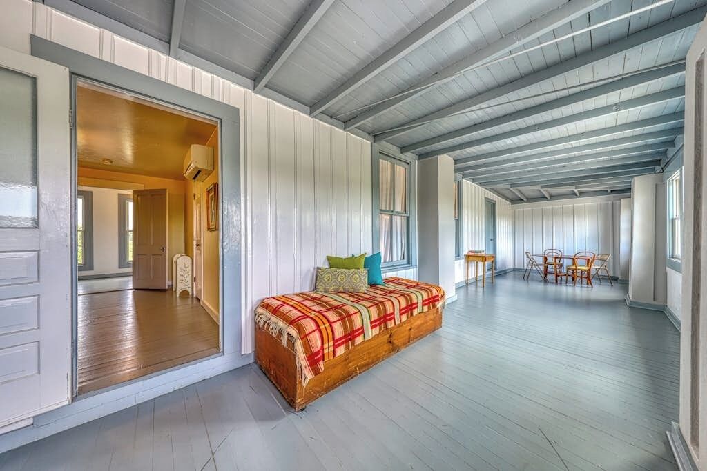 A spacious room with a wooden bench, a dining area, and a large window.