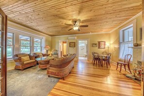 A spacious living room with a wooden ceiling, large windows, a dining area with a table and chairs, and a fireplace. - Historic Fredericksburg Farmhouse - Hill Country Views - Wine Trail - Snowbird (Fredericksburg)