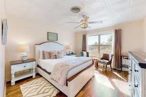 A bedroom with a bed, nightstands, a chair, a dresser, a ceiling fan, and a window with curtains. - Dog-friendly, Secluded Home 2 Miles to Main St. With Firepit, Gazebo & BBQ Pit (Fredericksburg)