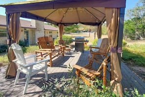 A covered outdoor seating area with wooden chairs and a grill. - Dog-friendly, Secluded Home 2 Miles to Main St. With Firepit, Gazebo & BBQ Pit (Fredericksburg)