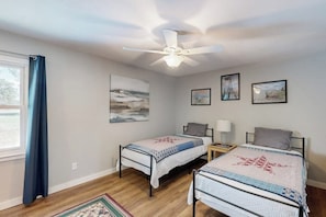 Ein Schlafzimmer mit zwei Betten, einem Deckenventilator und Bildern an den Wänden.