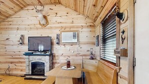 Ein Blockhaus-Interieur mit Kamin aus Stein, Holzbänken, einem Fernseher und montierten Tierköpfen.